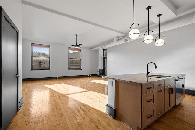 kitchen with a sink, a center island with sink, and light wood-style floors