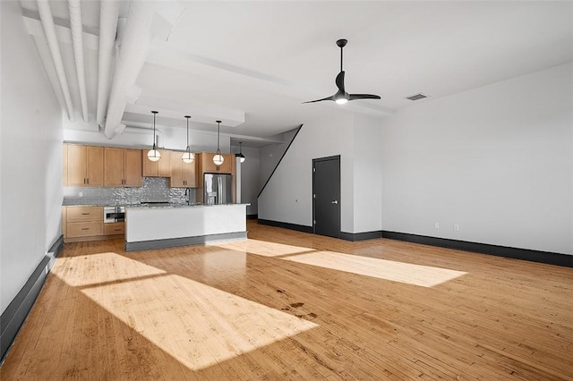 kitchen featuring light wood-style flooring, visible vents, stainless steel fridge with ice dispenser, decorative backsplash, and light brown cabinetry