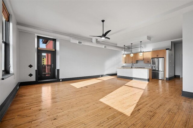 unfurnished living room featuring hardwood / wood-style flooring, baseboards, visible vents, and ornamental molding