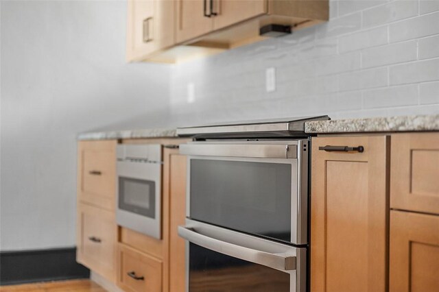 kitchen with tasteful backsplash, light wood-type flooring, stainless steel electric range, and light brown cabinetry