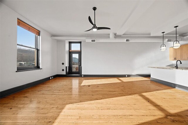 unfurnished living room with visible vents, ceiling fan, hardwood / wood-style flooring, and baseboards