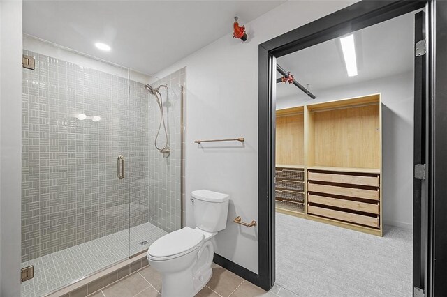 bathroom with baseboards, a shower stall, toilet, and tile patterned floors