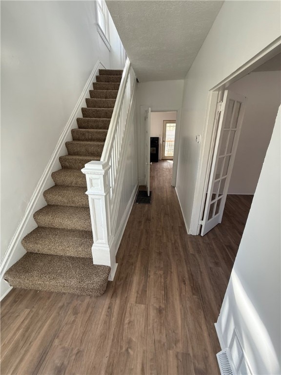 stairs featuring a textured ceiling, baseboards, and wood finished floors