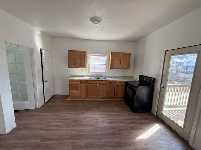 kitchen featuring dark wood-style floors, electric range, brown cabinetry, a sink, and a textured ceiling