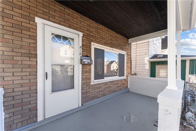 view of exterior entry with covered porch and brick siding