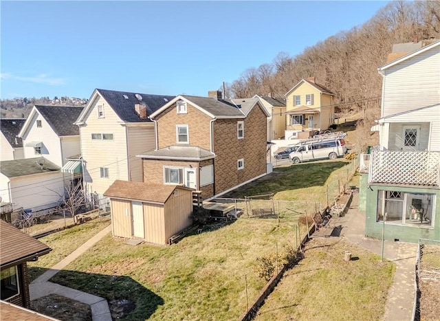 view of yard with an outbuilding, a fenced backyard, a residential view, and a shed