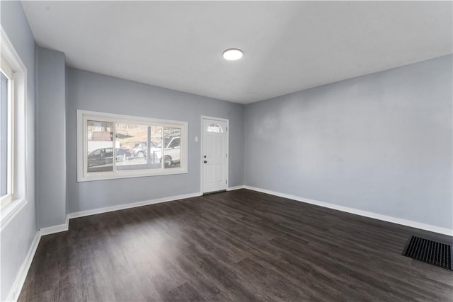 foyer entrance with dark wood finished floors, visible vents, and baseboards