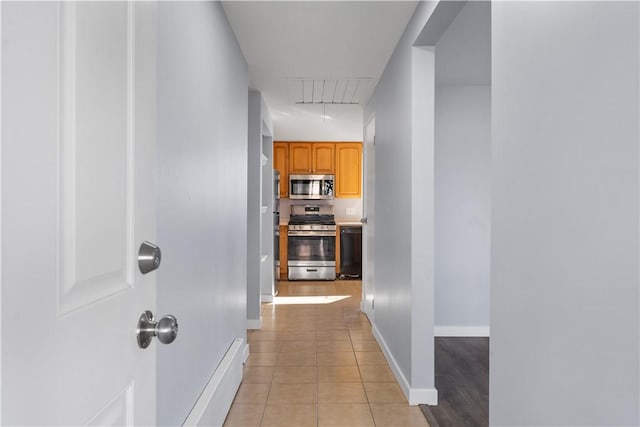 corridor with light tile patterned floors, attic access, and baseboards