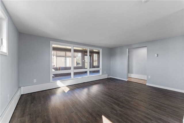 spare room with baseboards, wood finished floors, and a healthy amount of sunlight