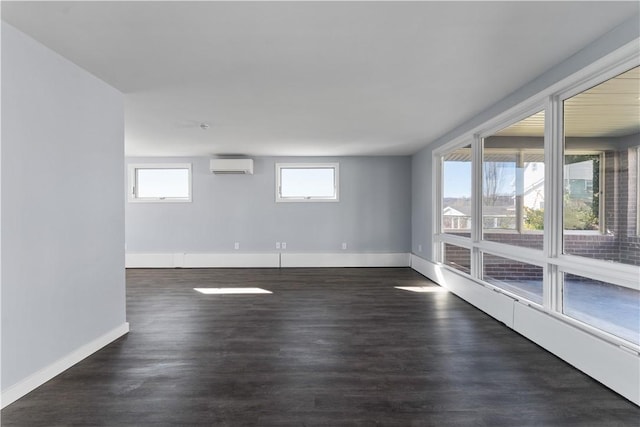 spare room featuring dark wood-style floors, a wall mounted air conditioner, and baseboards