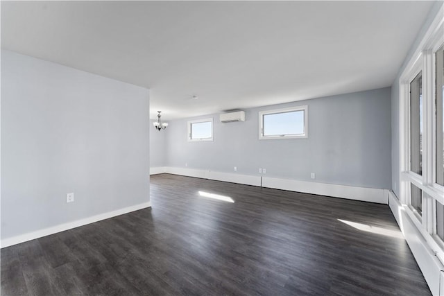 spare room with dark wood-type flooring, a wall unit AC, a notable chandelier, and baseboards