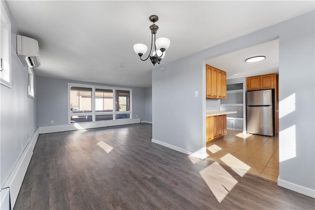 unfurnished living room with wood finished floors, baseboards, an inviting chandelier, and a wall mounted AC