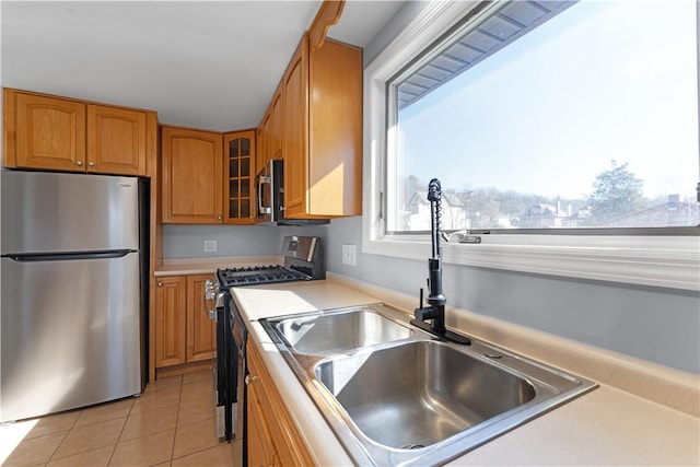 kitchen featuring stainless steel appliances, plenty of natural light, a sink, and light tile patterned flooring