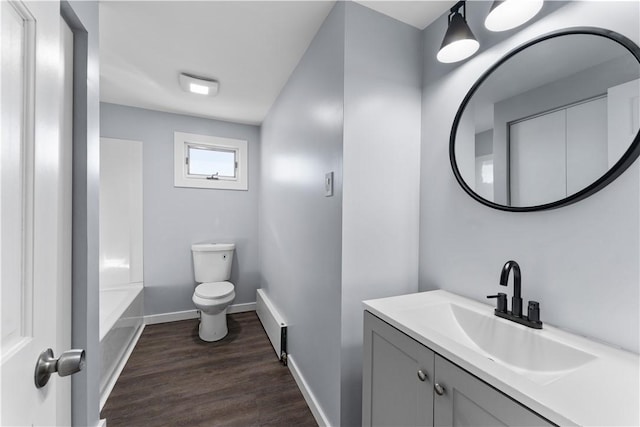 full bath with a tub to relax in, toilet, wood finished floors, vanity, and baseboards