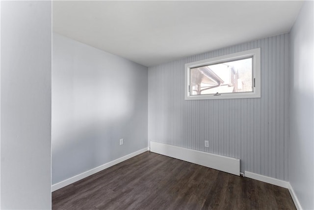 empty room featuring dark wood-style floors and baseboards