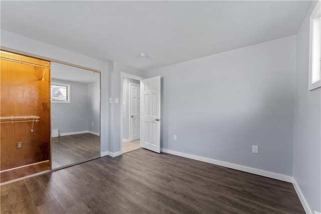 unfurnished bedroom featuring dark wood-style floors, a closet, and baseboards