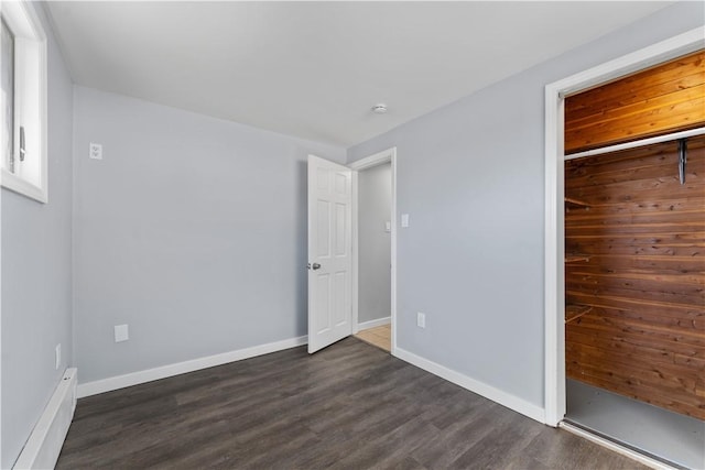 unfurnished bedroom featuring dark wood-style floors, a closet, and baseboards