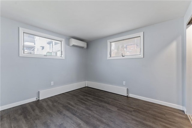 spare room with a wall mounted AC, dark wood finished floors, and baseboards