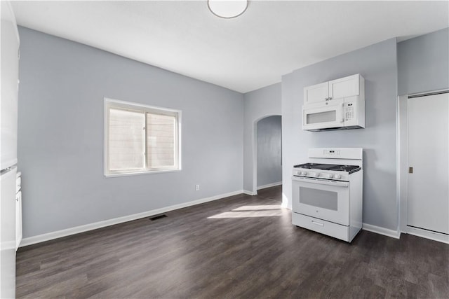 kitchen with arched walkways, white appliances, dark wood-type flooring, visible vents, and baseboards