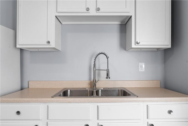 kitchen with white cabinetry, light countertops, and a sink