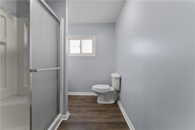 bathroom with toilet, a shower stall, baseboards, and wood finished floors