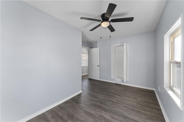 unfurnished room featuring visible vents, dark wood-style flooring, a wealth of natural light, and baseboards