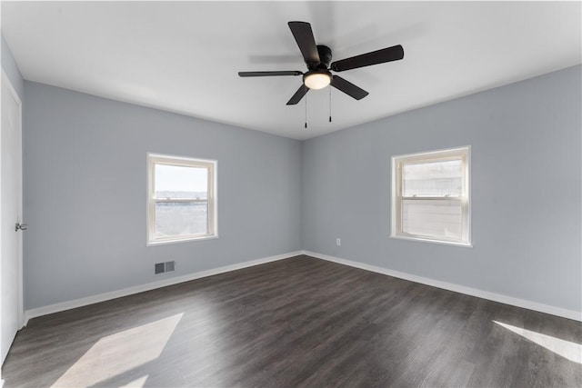 empty room featuring ceiling fan, dark wood-style flooring, visible vents, and baseboards