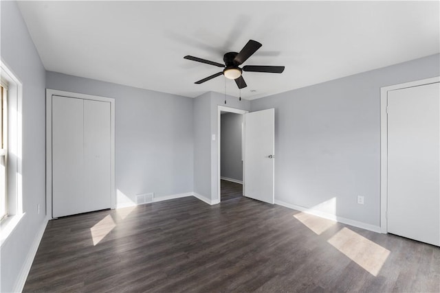 unfurnished bedroom with dark wood-type flooring, visible vents, baseboards, and a ceiling fan