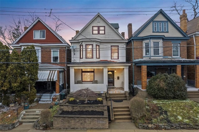 view of front of property with a porch, brick siding, and a balcony