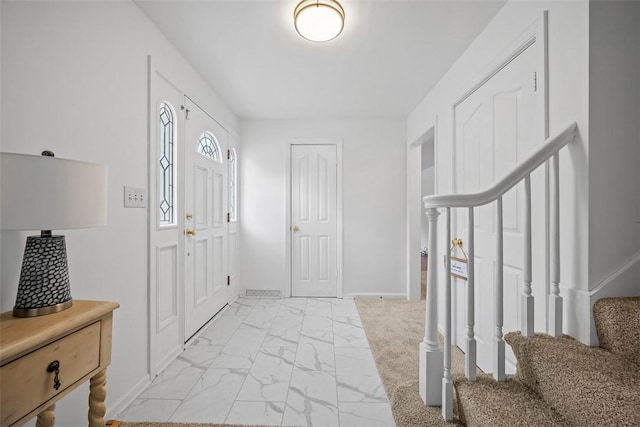 entrance foyer with stairs, marble finish floor, and baseboards