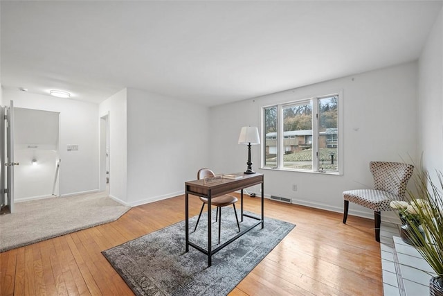 office space with light wood-style floors, baseboards, and visible vents