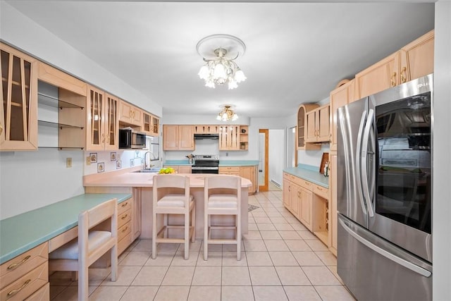 kitchen with a chandelier, light brown cabinets, a peninsula, a sink, and appliances with stainless steel finishes