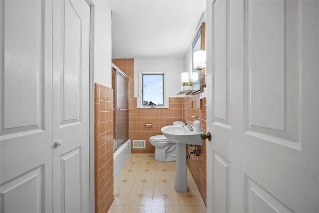 bathroom featuring toilet, a sink, visible vents, tile walls, and tile patterned floors