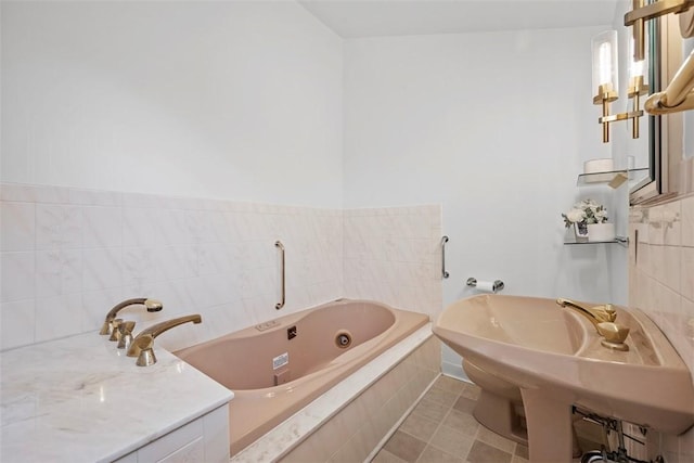 full bathroom featuring a sink, a whirlpool tub, and tile patterned floors