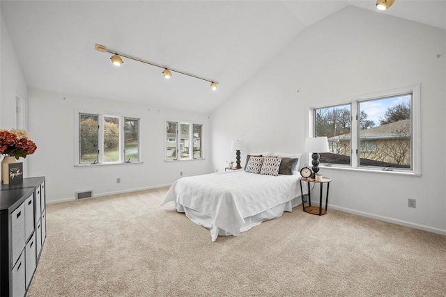 bedroom with light colored carpet, rail lighting, visible vents, high vaulted ceiling, and baseboards