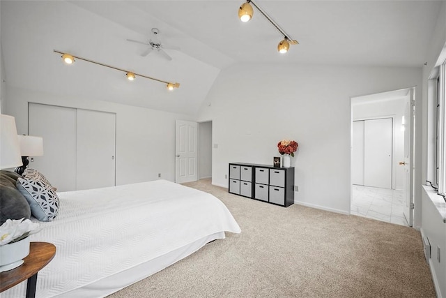 bedroom featuring a closet, baseboards, light colored carpet, vaulted ceiling, and track lighting