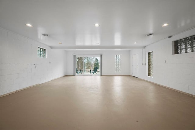 empty room with concrete block wall, visible vents, concrete flooring, and recessed lighting