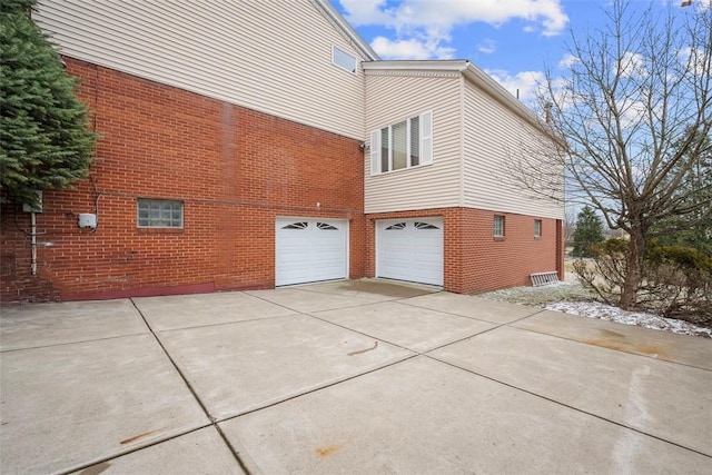 view of property exterior featuring an attached garage, concrete driveway, and brick siding