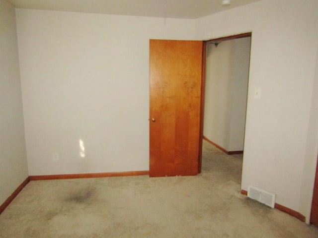 empty room with carpet, visible vents, and baseboards