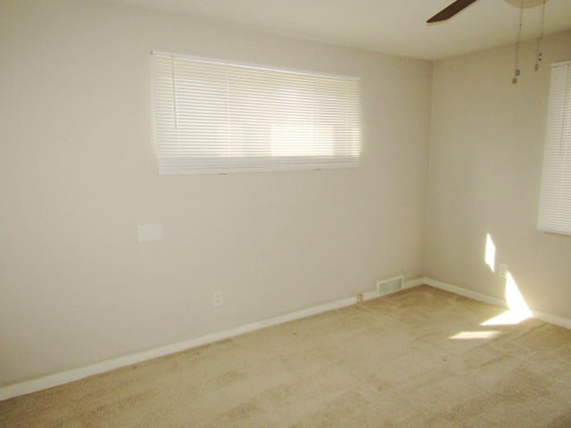 spare room featuring carpet, visible vents, baseboards, and a ceiling fan