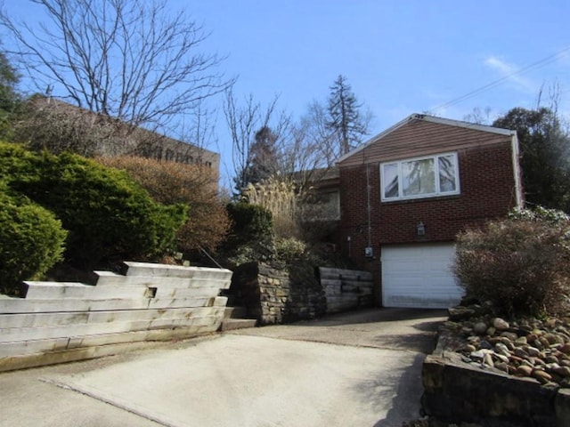 view of side of property with concrete driveway, brick siding, and an attached garage