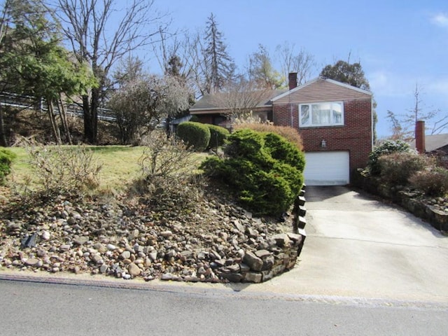 view of front of home featuring brick siding, driveway, a chimney, and an attached garage