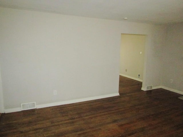 spare room with wood finished floors, visible vents, and baseboards