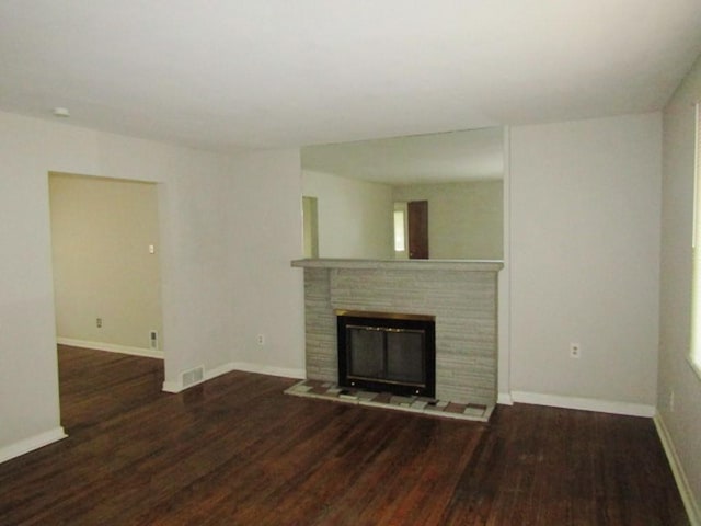 unfurnished living room featuring visible vents, baseboards, wood finished floors, and a glass covered fireplace