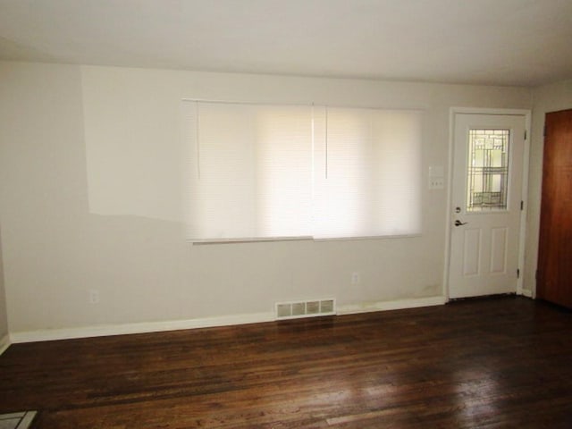 unfurnished room with baseboards, visible vents, and wood finished floors