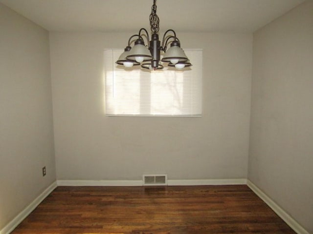 unfurnished dining area featuring a notable chandelier, baseboards, visible vents, and wood finished floors