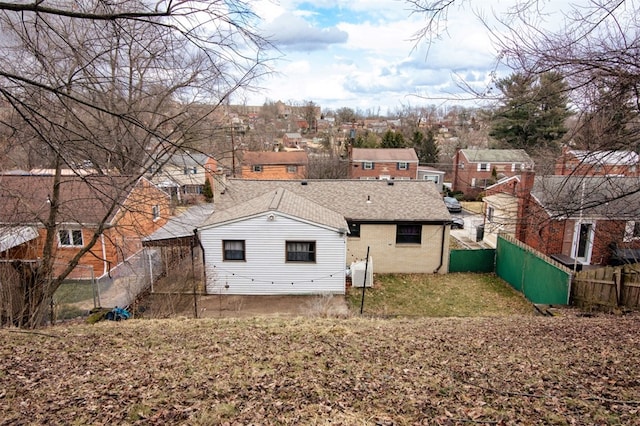 rear view of property featuring a shingled roof, a fenced backyard, and brick siding