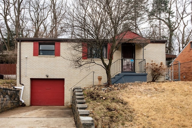 view of front facade with a garage, driveway, brick siding, and fence