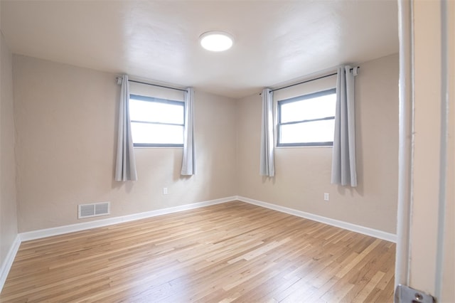 empty room with light wood-type flooring, baseboards, and visible vents