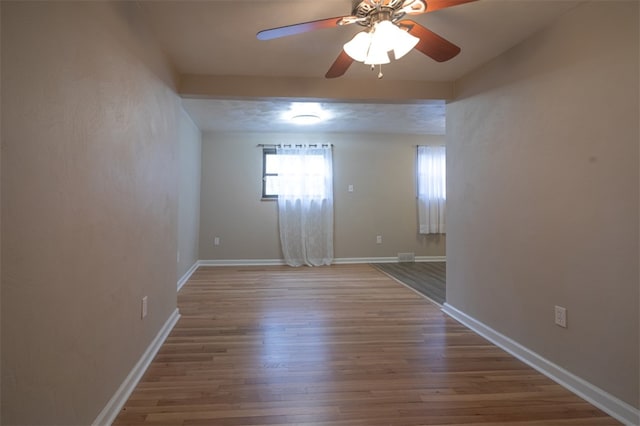 spare room with ceiling fan, wood finished floors, and baseboards